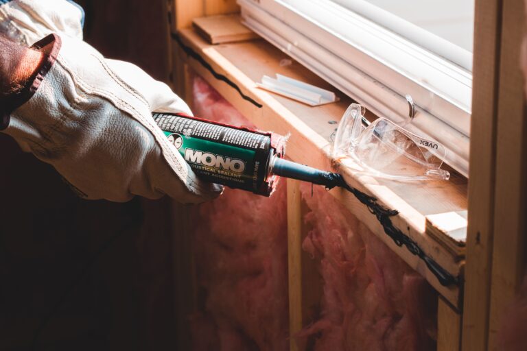 Pencere birleşim yerine sızdırmazlık mastiği uygulayan işçinin ellerinin yakın çekimi